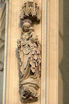 Archivo:Escultura de la Virgen María en la torre norte del siglo XV. En la peana se aprecia la figura de un músico que toca un rabel de tres cuerdas.jpg